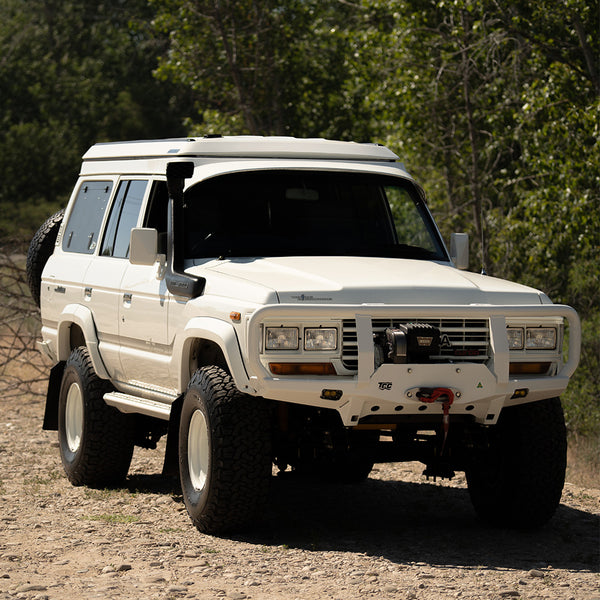 White off-road vehicle on a dirt road with trees in the background