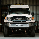 White Toyota vehicle with large off-road tires in a garage setting