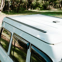 White vehicle with a roof rack in a forest setting