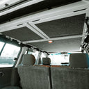 Car interior with an open roof panel showing soundproofing material.