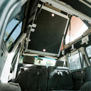Open-top vehicle interior with a sunroof and side windows open, showing a scenic view outside.