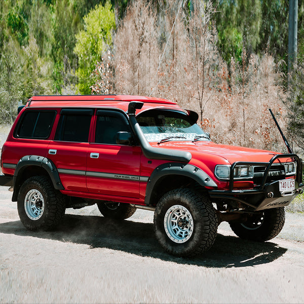 Red off-road vehicle on a road with trees in the background