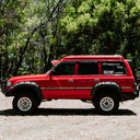 Red SUV parked on a dirt road with trees in the background