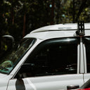 White SUV with a roof rack and light in a forest setting