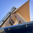 Close-up of a beige tent with a blue roof against a clear blue sky.