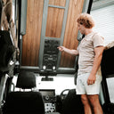 Man interacting with control panel inside a vehicle, possibly an RV or camper.