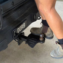 Person using a tow bar on a vehicle with visible license plate 'DQ RB'.