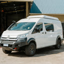 A white Toyota Hiace van with an pop top roof conversion, black roof rack