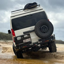 White Toyota SUV with a spare tire on a muddy off-road terrain