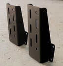 Two black metal brackets on a gray concrete surface